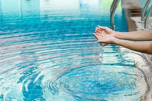 la mano e l'acqua toccano l'acqua blu. per rinfrescare il concetto di giocare con acqua pulita con spazio di copia. foto