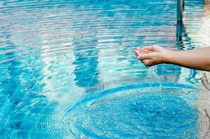 la mano e l'acqua toccano l'acqua blu. per rinfrescare il concetto di giocare con acqua pulita con spazio di copia. foto