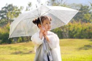 una bambina era felicemente in piedi sotto un ombrello contro la pioggia foto