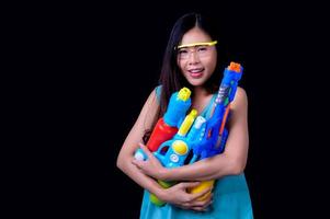 una bella donna asiatica mostra un gesto mentre tiene in mano una pistola ad acqua di plastica durante il festival di Songkran foto