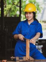 donne che lavorano in uniforme da meccanico utilizzando strumenti di lucidatura del legno per regolare le assi foto