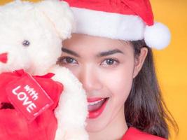 bella ragazza asiatica in costume rosso da Babbo Natale e orso d'amore nel giorno della celebrazione foto