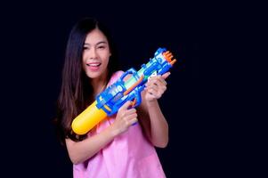 una bella donna asiatica mostra un gesto mentre tiene in mano una pistola ad acqua di plastica durante il festival di Songkran foto