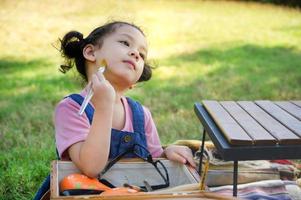 una bambina è seduta sul panno e dipinta sul viso, partecipa all'apprendimento e al gioco fuori dalla scuola nel parco naturale foto