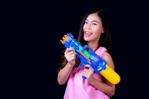 una bella donna asiatica mostra un gesto mentre tiene in mano una pistola ad acqua di plastica durante il festival di Songkran foto