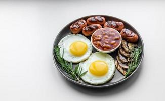 colazione inglese completa con fagioli, uova fritte, salsicce arrosto, pomodori e funghi foto