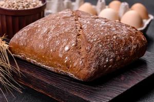 bel pane nero gustoso e di forma quadrata su uno sfondo di cemento scuro foto