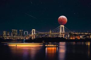 bella luna arancione sul ponte e una città moderna. concetto di viaggio e industria. foto