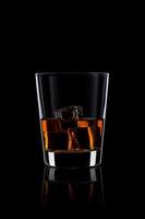 bicchiere con whisky e ghiaccio sul nero
