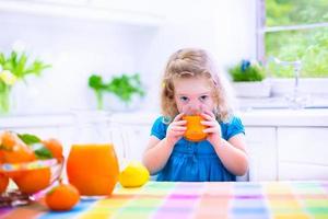 bambina che beve il succo di arancia foto