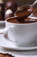 sgocciolatura del cioccolato dal cucchiaio in un primo piano della tazza foto