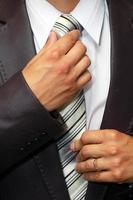 mani dell'uomo che riparano la cravatta foto