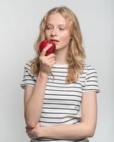 ritratto di giovane donna sorridente che morde la mela rossa. viso fresco, bellezza naturale foto