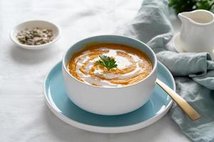 zuppa di zucca con latte di cocco, piatto vegetariano, cibo sano e dietetico su tovaglia bianca foto