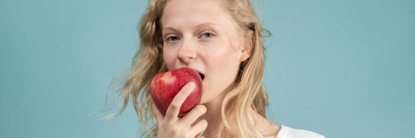 banner a larghezza lunga con ritratto di giovane donna che morde la mela. viso fresco, bellezza naturale, foto