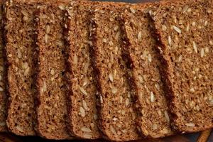 pane di grano di segale tostato su un tagliere di legno su sfondo marrone scuro. foto