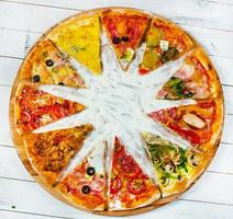 diverse fette di pizza con condimenti diversi su uno sfondo bianco. tagliare a fette una deliziosa pizza fresca. gustosa pizza su bianco.