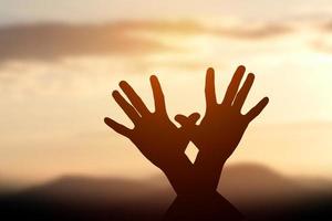 silhouette di mani femminili durante il tramonto foto