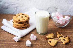 biscotti fatti in casa con latte e marshmallow d'aria su asciugatutto e tavolo di legno. Buongiorno. concetto di colazione