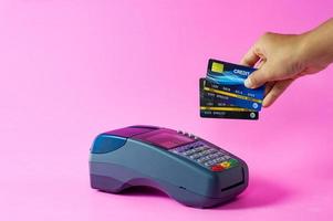 carta di credito strisciare due crediti manualmente attraverso un terminale di pagamento. concetto di spreco eccessivo foto