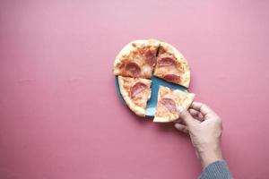 vista dall'alto della mano dell'uomo che raccoglie una fetta di pizza da un piatto foto