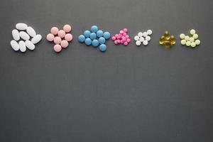 vista dall'alto di eventuali pillole e capsule colorate su sfondo nero foto