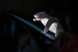 primo piano della mano del giovane utilizzando lo smartphone di notte foto