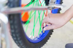 fuoco selettivo della mano del ragazzo che fissa i concetti di bicicletta, hobby meccanico e riparazione foto