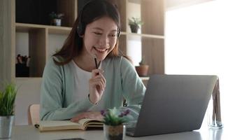 studenti asiatici curiosi mentre studiano online su Internet e insegnanti di videoconferenza su laptop a casa. foto