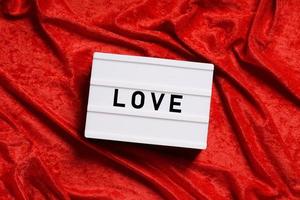 scatola luminosa di parole d'amore su sfondo di velluto rosso foto