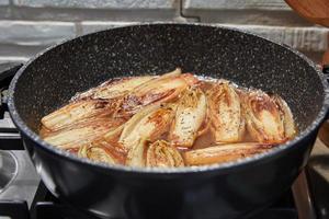 stufato di cicoria in padella su fornello a gas secondo ricetta da internet foto