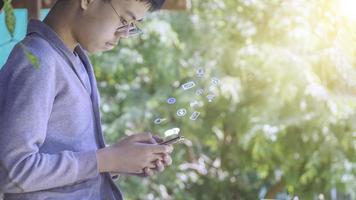 il ragazzo con gli occhiali che usa lo smartphone con i social media con le icone, vive in vacanza e gioca sui social media concetto uomo d'affari che usa telefono, social, media, marketing con icone funzionali. foto