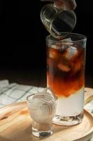miscelazione fresca di caffè arabica con succo di cocco dolce per l'assistenza sanitaria da bere a casa. bevande in estate su sfondo scuro copia spazio. foto