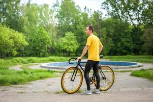 un giovane si è fermato a riposare con la sua bicicletta in un parco pubblico. foto