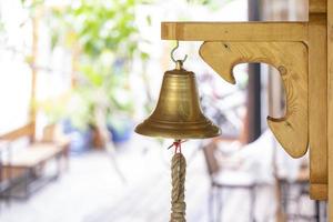 campana in ottone mano sul grande piatto di legno bastone sulla parete del palo. foto