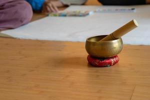 ciotola di ottone sulla base di stoffa giaceva sul pavimento di legno. è l'espediente vintage asiatico per far suonare un segnale e un suono per avvisare il seminario e il workshop per l'attenzione all'oratore. foto