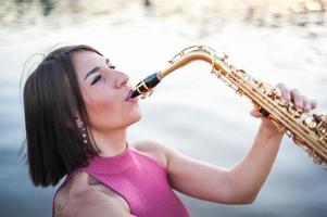 donna che suona il sassofono al tramonto. foto