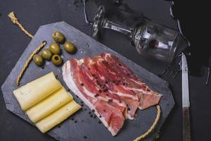arrangiamento di prosciutto con formaggio, olive e vino versato