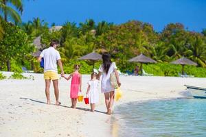 vista posteriore della giovane famiglia sulla spiaggia durante le vacanze estive foto