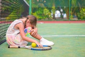 piccola ragazza triste sul campo da tennis foto