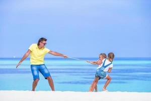 il giovane padre e le bambine si divertono insieme durante le vacanze tropicali foto