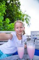 bambine che si fanno selfie e bevono gustosi cocktail al resort tropicale foto