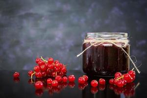 vasetto con marmellata di ribes rosso su sfondo scuro foto