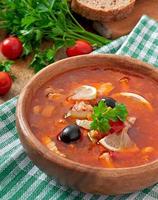 zuppa di solyanka russa con carne, olive e cetriolini in una ciotola di legno foto