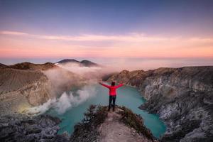 donna in piedi sulla cresta del vulcano attivo con fumo di zolfo al mattino foto