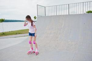 ritratto di una favolosa giovane donna con i rollerblade sulla pista di pattinaggio all'aperto. foto