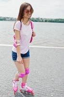 ritratto di una bella giovane donna in abbigliamento casual che pattina sul marciapiede del parco. foto