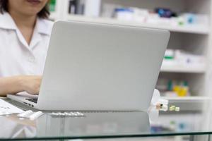 farmacista con computer portatile e farmaci in farmacia foto