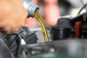 versando olio motore al motore dell'auto. olio fresco versato durante il cambio dell'olio in un'auto. foto