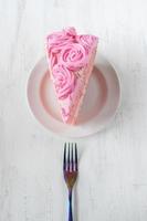 fetta sottile festiva di torta di compleanno rosa con fiori a velo e forchetta piatta foto